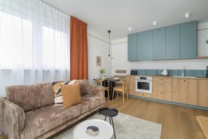 a living room with a couch and a kitchen at Unique 2-Bedroom Apartment on the 10th Floor with FREE GARAGE Poznań by Renters in Poznań