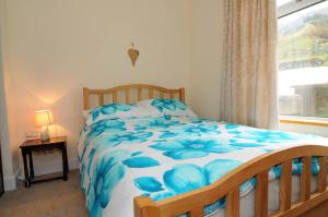Un dormitorio con una cama azul y blanca y una ventana en Gerlan Llangrannog, en Llangranog