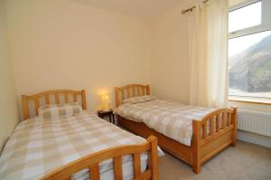 Dos camas en una habitación con ventana. en Gerlan Llangrannog, en Llangrannog 5 fotos más