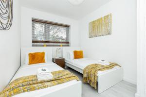 two beds in a room with white walls at Newly refurbished 2BR wbalcony in Vibrant Peckham in London