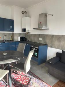 a kitchen with blue cabinets and a table and a couch at Düs Apartment 2 in Düsseldorf