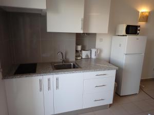 a kitchen with white cabinets and a sink and a refrigerator at Great value 5 mins to Praia de Rocha beach in Portimão +5 photos