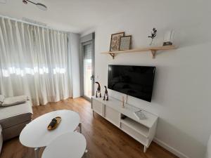 sala de estar con TV de pantalla plana en la pared en Jardines del Porvenir 2 en Puerto Real