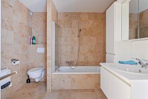 ein Badezimmer mit einer Badewanne, einem WC und einem Waschbecken in der Unterkunft Harbour View 2a 2ev in Zeebrugge