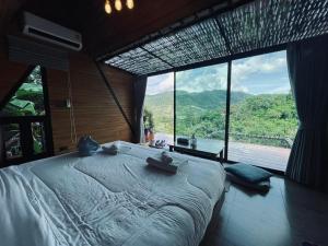 a bedroom with a large bed with a large window at Camp Mai Mee Chue in Pong Yaeng