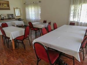 ルサカにあるKALIYANGILE GUEST HOUSEの白いテーブルと赤い椅子が備わる部屋