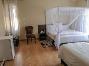 a bedroom with a canopy bed and a chair at KALIYANGILE GUEST HOUSE in Lusaka