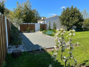 a yard with a fence and a garden with a bush at Les logis de Simon in La Flotte