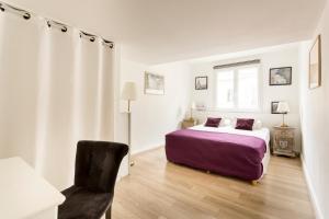 a white bedroom with a bed and a chair at Artois Champs-Elysées in Paris