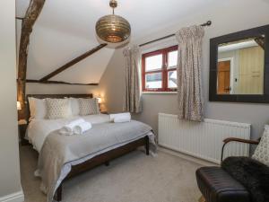 1 dormitorio con cama, espejo y silla en The Old Cider House, en Worcester