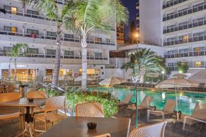 a hotel with a pool and tables and palm trees at Sandos Griego in Torremolinos