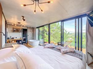 une chambre avec un grand lit avec une grande fenêtre dans l'établissement CNB - Cabanas Vista Serra em Campos do Jordão, à Campos do Jordão