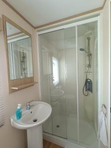 a white bathroom with a shower and a sink at Laurel 20 holidayhome in Rhyl