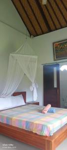 a bedroom with a large bed with a canopy at Lumbung Sari Home Stay in Amed