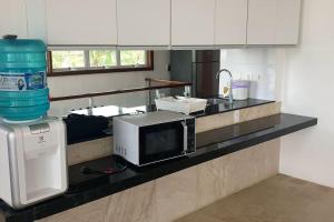 um balcão de cozinha com um micro-ondas e um lavatório em Casa em resort na Taiba em São Gonçalo do Amarante