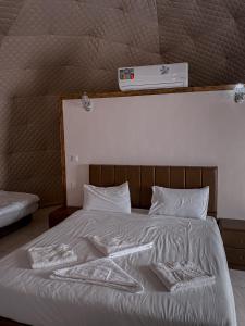Una cama con sábanas blancas y almohadas con un termómetro encima. en RUM MAGiC lUXURY CAMP, en Wadi Rum