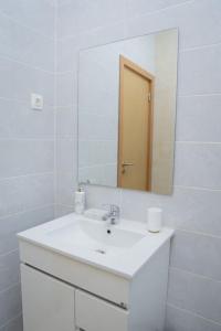 a white bathroom with a sink and a mirror at Rose de Palmarejo Grande T2 in Praia