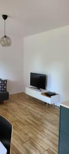 a living room with a tv on a white wall at Lovely One-Bedroom Condo With Patio. in Warsaw