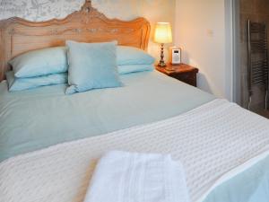 a large white bed with blue pillows and a lamp at Apartment 2 - Rosewarne Manor in Praze an Beeble
