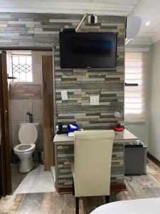 a bathroom with a toilet and a television on a wall at elim glamour hotel in Elim