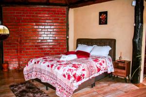 Cama en habitación con pared de ladrillo en Oásis Pousada en Cambará