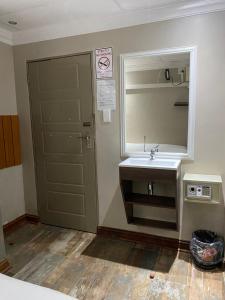 uma casa de banho com um lavatório, um espelho e uma porta em elim glamour hotel em Elim
