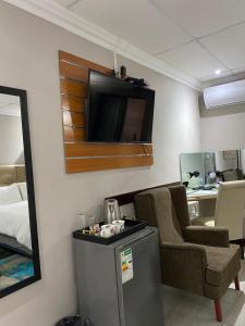 um quarto com uma televisão, uma cadeira e uma cama em elim glamour hotel em Elim