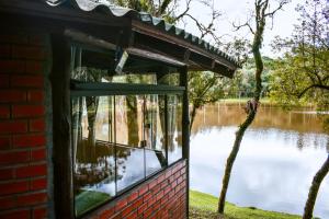 a window in a brick building looking out at a lake at Oásis Pousada in Cambará