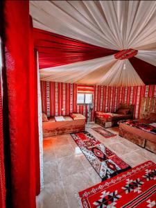 una sala de estar con paredes rojas y cortinas rojas. en RUM MAGiC lUXURY CAMP, en Wadi Rum