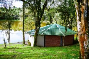 a small building with a green roof next to a lake at Oásis Pousada in Cambará +12 photos