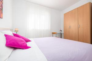 1 dormitorio con 1 cama blanca grande con almohadas rosas en Apartment Maya with sea view, en Poreč