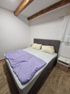 a bedroom with a large bed with purple sheets at Holiday Home Robert 2 with pool in Cesarica