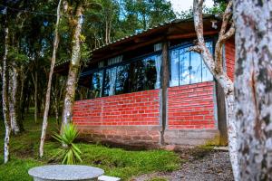 a brick house with a window in a forest at Oásis Pousada in Cambará
