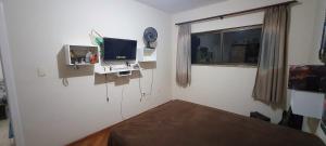 - une chambre avec un lit, une télévision et une fenêtre dans l'établissement Pousada e Hostel Sossego, à Luminárias
