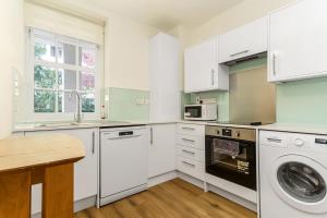 a kitchen with white cabinets and a washer and dryer at Very Central - Comfy & Quiet In Westminster For 4 in London