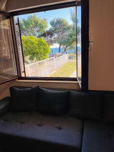 a couch sitting in a room with a window at Beachfront apartment Drazen, with garden in Split