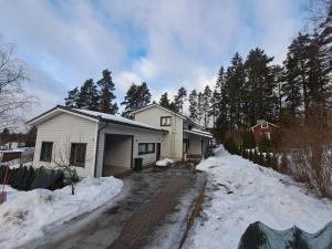 a house with snow on the ground next to a driveway at Tilava kaksio paritalosta in Kangasala