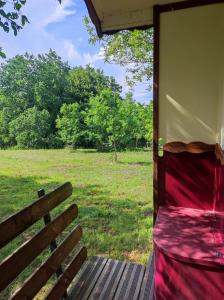 una cama en un porche con un campo en el fondo en La Roulotte Couzote, en Couze-et-Saint-Front