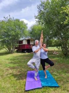 un hombre mayor y una mujer haciendo yoga en esterillas en La Roulotte Couzote, en Couze-et-Saint-Front