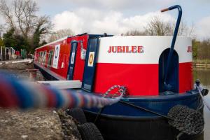 czerwona, biała i niebieska łódź w wodzie w obiekcie The Jubilee Narrow Boat w mieście Loughborough