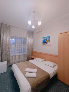 a bedroom with a bed with two towels on it at Altyn-Adam Hotel in Astana