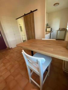 einen Holztisch und einen weißen Stuhl in der Küche in der Unterkunft Le Moulin de César in Vaison-la-Romaine