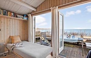 a room with a bed and a balcony with a view of the ocean at Beautiful Home In Dronningmlle With House Sea View in Dronningmølle
