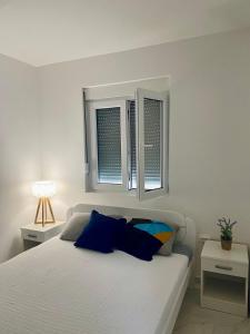 a white bed with blue pillows in a bedroom at Vini Apartments in Zagrađe