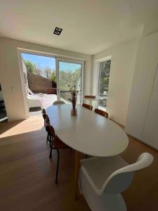 a dining room with a white table and chairs at Gezellig huis met open haard en fenomenale tuin in Koksijde