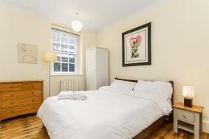 a bedroom with a large white bed and a dresser at Very Central - Comfy & Quiet In Westminster For 4 in London