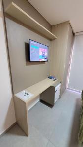 Habitación con escritorio y TV en la pared. en Flat em Bananeiras - PB, en Bananeiras