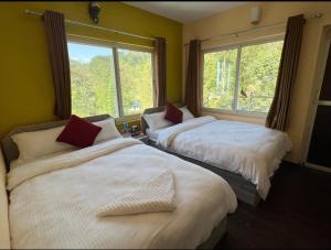 two beds in a room with a window at Hotel Village View Nagarkot in Nagarkot