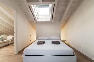 1 dormitorio con 1 cama blanca grande y tragaluz en Incanto Del Lago - Como Lake Cosy Apartment en Como