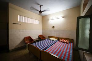 a bedroom with a bed and two chairs in it at Sri sai baba guest house in Puducherry